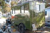 Photo shows rear end of 1929 REO Camping Wagon camper, with entry door and ladder up to roof top luggage rack