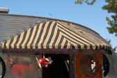 Photo of chocolate brown striped awning with brown fringe over entry door on a 1952 Airfloat vintage trailer 