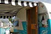 Picture of a 1956 Shasta 1500 trailer with a bold black and white canvas side awning