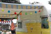 1957 Shasta vintage trailer with sky blue and lemon yellow striped canvas awning with white fringe