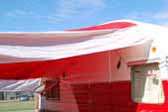 Wide red and white striped side awning on a 1957 Shasta vintage trailer