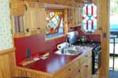 Very inviting kitchen in a 1959 Federal truck based camper features laminate countertop and tilt-out custom stained glass window