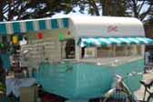 Photo of a 1961 Shasta vintage trailer with turquoise and white striped front and side awnings