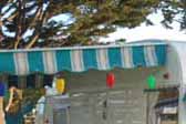 Turquoise and white striped awning with a turquoise scalloped border, on a 1961 Shasta vintage trailer