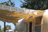 Yellow, brown and white striped side awning on a 1963 Airstream Flying Cloud trailer painted mustard yellow and white