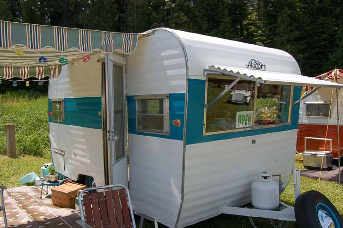 Photo of a beautiful vintage Aladdin trailer with a striped side awning and front fiberglass window shade