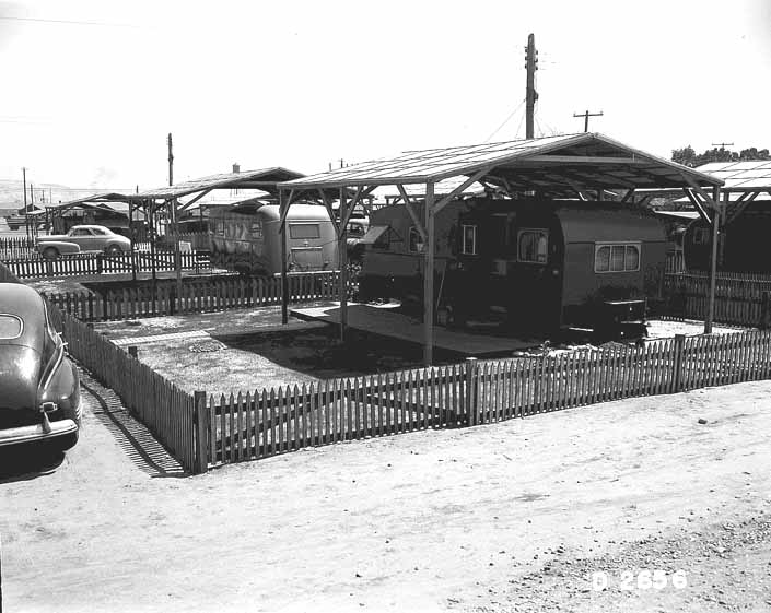 Government photo shows a wooden shade cover built over a beautiful 1940's vintage trailer, at the Hanford Trailer Camp in Washington