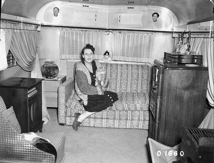 Government photo shows a woman relaxing on her trailer's couch with her cat, at the Project Hanford Trailer City in Washington