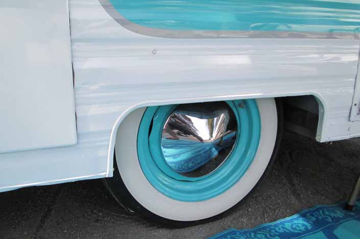 Photo shows an example of a vintage trailer wheel painted sky blue and with a pointy chrome hubcap