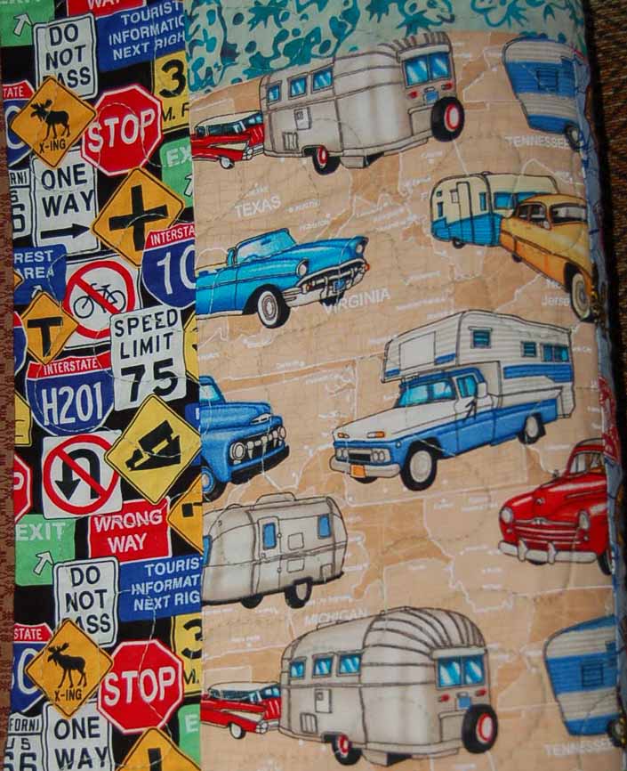 This photo shows a swatch of retro fabric with a vintage trailers, cars and trucks pattern