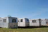 Photo provides a rear end view of a group of Spartan Manor trailers parked in a vintage trailer junkyard
