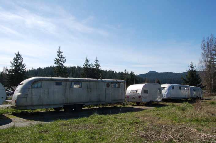 Row of Vintage travel trailers stored at a vintage trailer junkyard and awaiting restoration