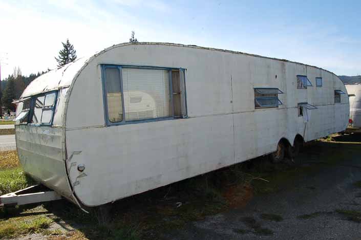 Vintage trailer junk yard has a long vintage Traveleze trailer in need of restoration
