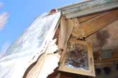 Photo shows an original cabinet door hanging in a rare Palace travel trailer stored in a vintage trailer junkyard