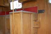 Original wood kitchen cabinets in a rare Palace travel trailer are in restorable condition and stored in a vintage trailer junkyard