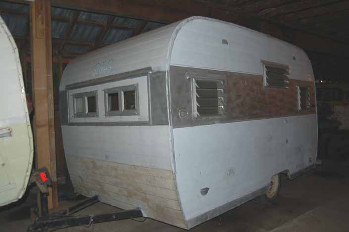 Vintage trailer storage yard has a small vintage Aloha trailer with altered windows, available for restoration