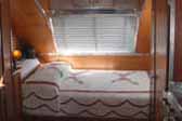 Cozy bed with a vintage chenille bedspread in a restored Aero Flite travel trailer