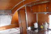 Beautiful wood paneling and cabinetry with stainless steel trim, in an Aero Flite vintage trailer