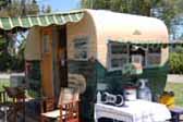 Restored vintage 1955 Aljoa Travel trailer painted green and white, with striped awnings