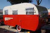 Classic 1955 Aljoa Travel Trailer riding on red rims with baby moon hubcaps and wide whitewall tires