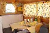 Vintage 1958 Aloha travel trailer dinette area decorated with cheerful yellow curtains and tablecloth