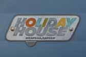 Original Holiday House logo emblem logo next to entryway door on 1960 vintage Holiday House travel trailer
