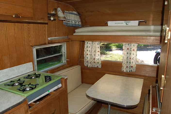 Original interior features sleeping quarters above the dining table in an original Aladdin Genie trailer