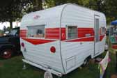 Photo shows the rear end of a red and white Magic Carpet vintage trailer built by the Aladdin Trailer Company