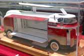 Photo of a detailed scale model of a GM Parade of Progress Futurliner bus with the roof light bar raised and the side panels open to showcase the exhibits inside