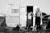 Government photo shows a young family with their 1940's vintage canned ham travel trailer, at the Hanford Trailer Camp in Washington