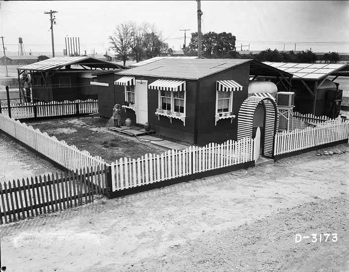 Government photo shows a cute and tidy family home next to their 1940's vintage trailer, at the Hanford Trailer Camp in Washington