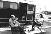 Vintage photo shows a family and their dog, sitting outside their 1940's vintage trailer, at the Hanford Trailer Camp in Washington