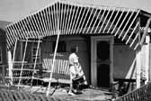 Vintage photo shows a woman visiting a family's home next to their 1940's vintage trailer, at the Hanford Trailer Camp in Washington