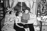 Vintage photo of a mother reading to her son next to the Christmas tree in a vintage trailer, at the Project Hanford Trailer City in Washington