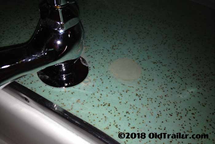Image is a detailed view of the patched and repaired holes in the vintage formica on our countertop