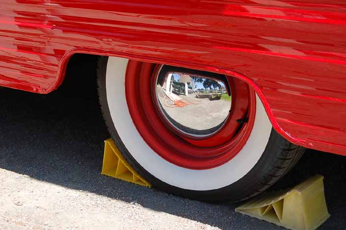 Photo shows an example of a vintage trailer wheel painted orange, and with a chrome hubcap and wide whitewall tires