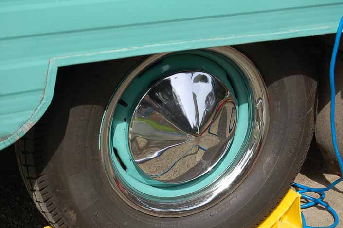 Photo shows an example of a vintage trailer with wheels painted Turquoise green, with chrome hubcaps and beauty rings