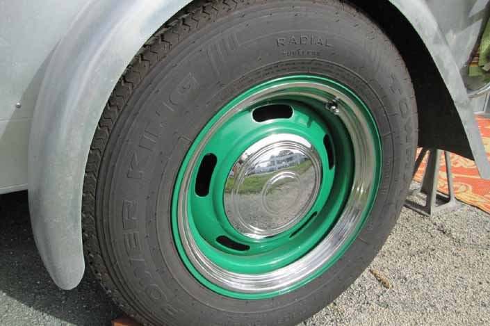 Photo shows an example of a vintage trailer with wheels painted green, with chrome hubcaps and beauty rings