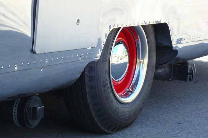 This image shows an example of vintage trailer wheels painted red, with small baby moon hubcaps and beauty rings