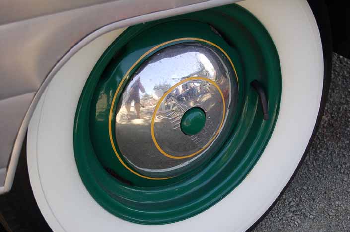 Photo shows an example of a vintage trailer with wheels painted forest green with yellow pinstripe, chrome hubcaps and wide whitewall tires