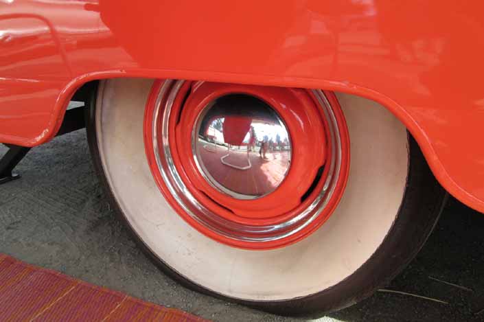 Photo shows an example of a vintage trailer with wheels painted orange and with bay moon hubcaps and beauty rings and wide ww tires