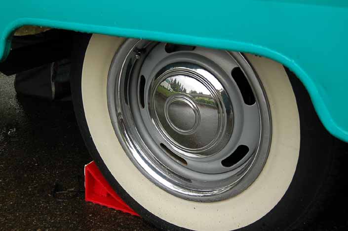 Photo shows an example of a vintage trailer with wheels painted silver, with chrome hubcaps, beauty rings and wide ww tires