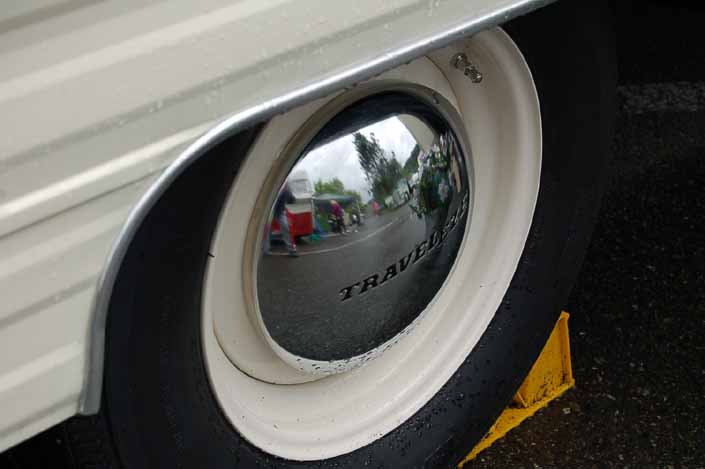 Photo shows an example of a vintage trailer with wheels painted white, with chrome hubcaps