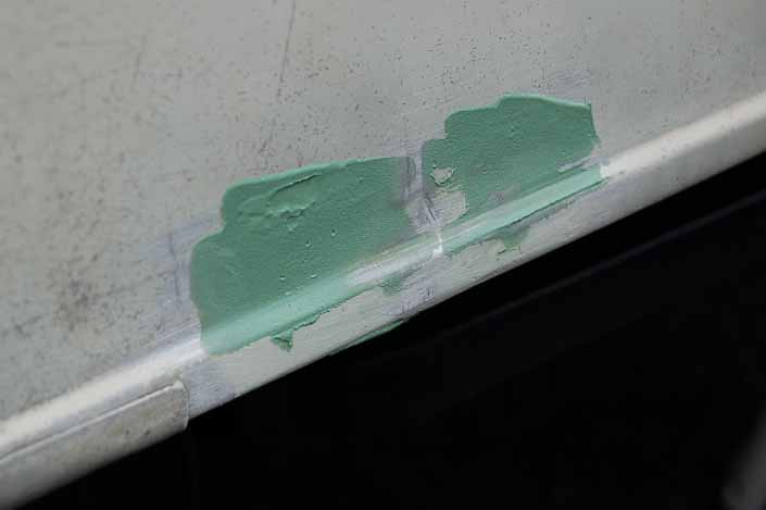 Picture shows dents in a vintage camper trailer being repaired with epoxy filler