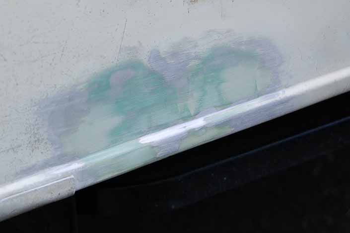 Photo shows a repaired dent in a vintage camper trailer sanded smooth and flat