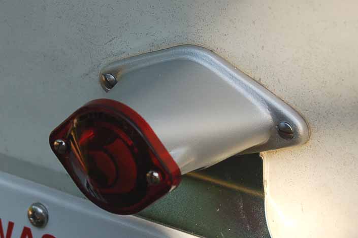Picture shows that the vintage trailer license plate light housing restoration has been completed with a new red bulb lens