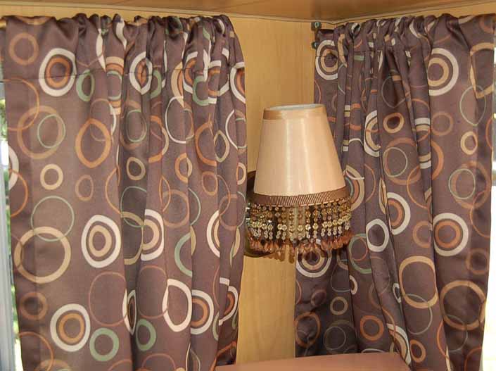 This photo shows a swatch of retro fabric with a 1960's circles graphics pattern on a brown background, for your vintage trailer