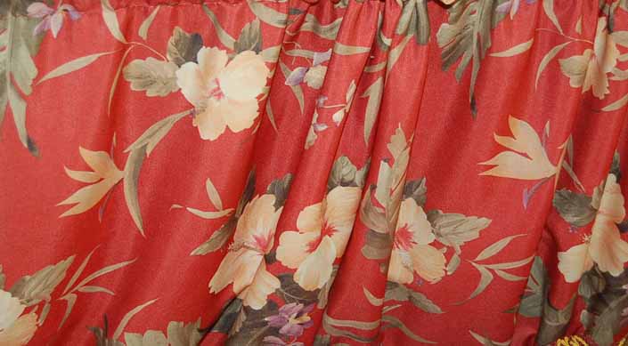 This photo shows a swatch of retro fabric with a tropical flowers pattern on a red background, for your vintage trailer