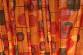 This photo shows a swatch of retro fabric with a mid-century geometrics pattern on an orange background, for your vintage trailer