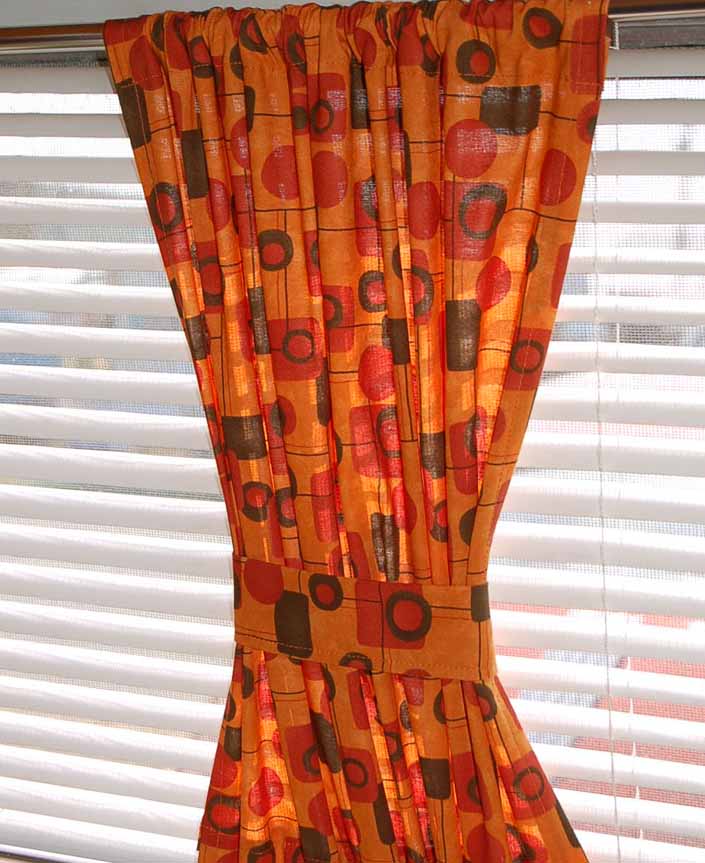 This photo shows a swatch of retro fabric with a mid-century geometrics pattern on an orange background, for your vintage trailer